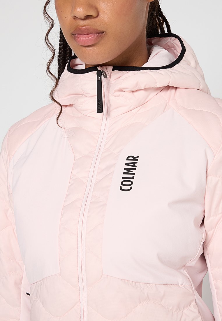 Giacca a vento rosa chiaro con texture trapuntata, dettagli neri, cappuccio e logo sul davanti. Presenta una cerniera completa e un pannello in contrasto.