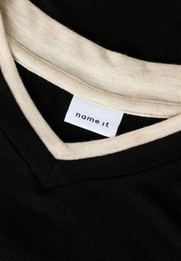 Must musta kaelus kontrastse beeži soonikuga ja riidest sildiga, millel on kiri "name it", näidates V-kaelusega kujundust.