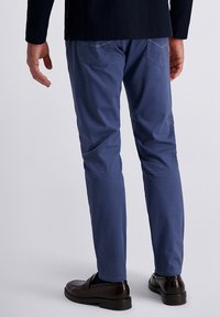 Schmale blaue Hosen aus leichtem Stoff, mit zwei Gesäßtaschen und einem einfachen Saum, kombiniert mit dunklen Lederschuhen.