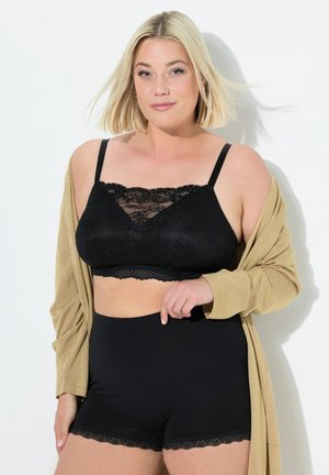 Zwarte kanten bralette met verstelbare bandjes, gecombineerd met hoge zwarte Shorts met kantafwerking, afgewerkt met een gouden cardigan.