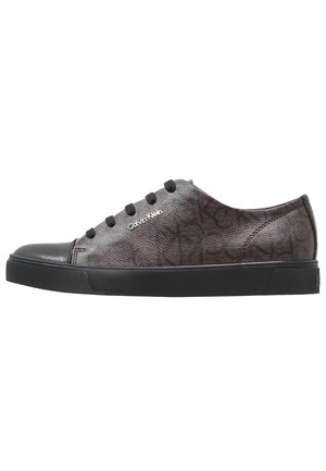 Flach geschnittener dunkelgrauer Calvin Klein Sneaker mit schwarzer Gummisohle, schwarzer Zehenkappe, schwarzen Schnürsenkeln und dezentem eingeprägtem Logo-Muster.