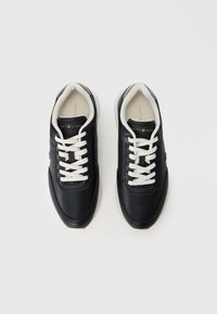 Black leather sneakers with white laces and a rubber sole. Features a smooth texture and branding on the side and insole.