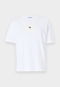 Weißes Baumwoll-T-Shirt mit einem quadratischen, strukturierten Patch auf der Brust, der mit schwarzem Logo-Detail versehen ist. Rundhalsausschnitt und kurze Ärmel.