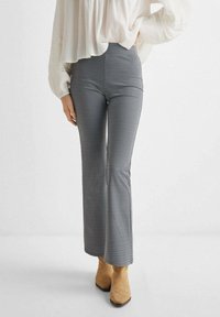 Byxor i ett svartvitt geometriskt mönster, med en utsvängd bendesign. Bärs med ljusa, högklackade stövlar.