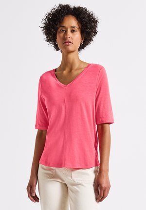 Kurzärmliges V-Ausschnitt-Oberteil aus leuchtend pinkem Stoff, mit einem lockeren Schnitt und einer dezenten Mittelnaht. Glatte Textur ohne sichtbare Musterdetails.