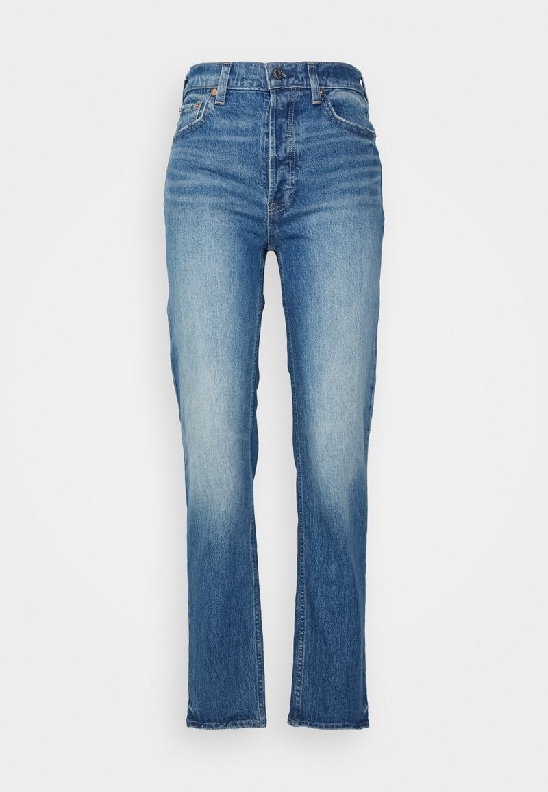 Jean en denim bleu taille haute avec cuisses délavées, fermeture avant par bouton et fermeture éclair, et design à cinq poches, présenté à plat sur fond blanc.