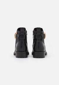Bottines noires en cuir avec une finition lisse, présentant un détail de boucle sur le côté, des panneaux élastiques et une semelle robuste avec un cramponnage.