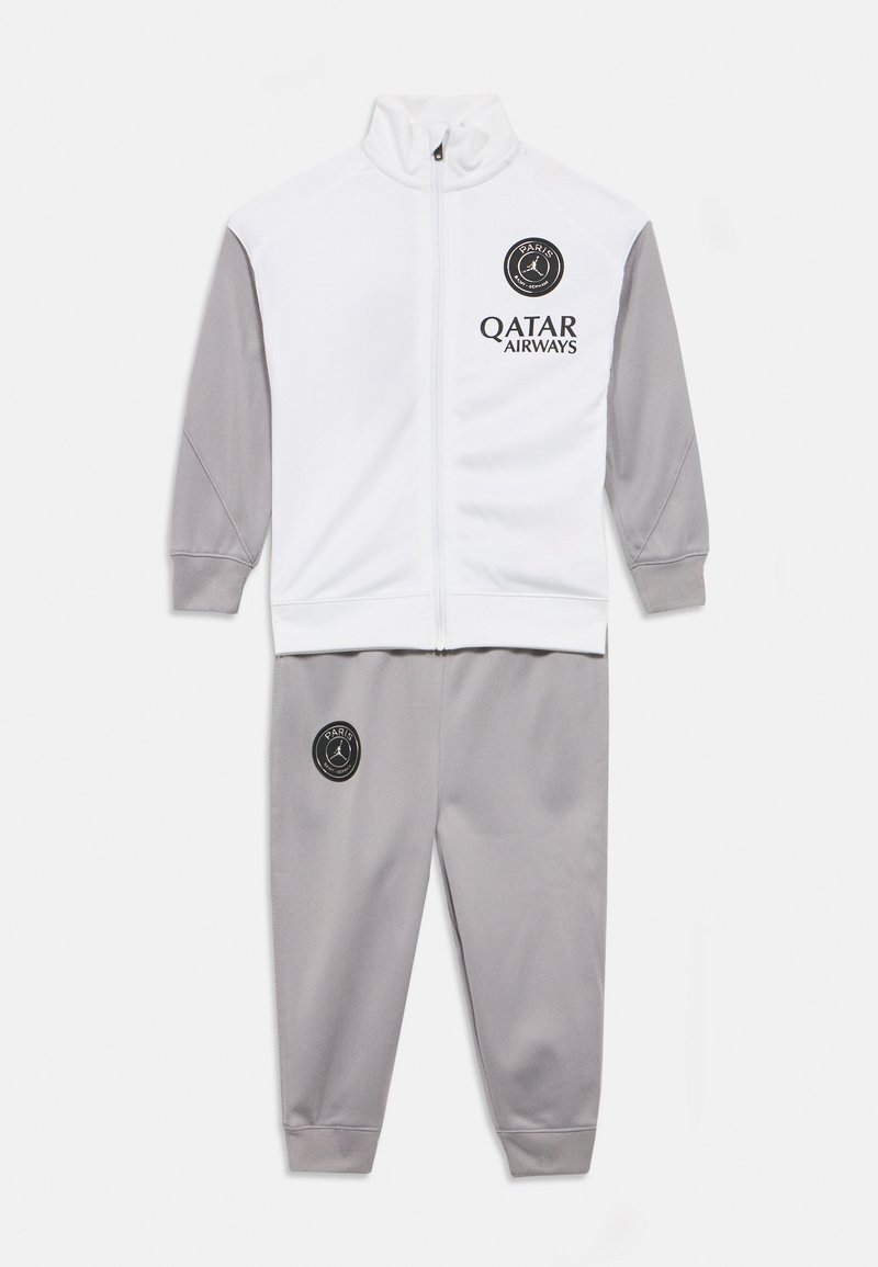 Λευκή και γκρι φόρμα με μπουφάν πλήρους φερμουάρ που έχει τα λογότυπα του Paris Saint-Germain και της Qatar Airways.