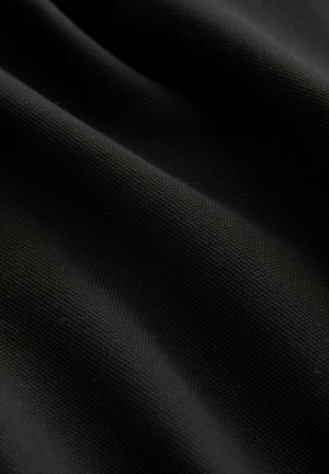 Tela negra texturizada con un patrón tejido, mostrando suaves pliegues y caídas, enfatizando su superficie lisa y uniforme.