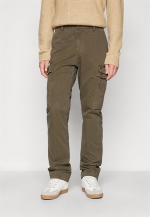 Pantaloni cargo verde oliva con tasche laterali, realizzati in cotone. Presentano una vestibilità rilassata e sono abbinati a sneakers bianche.