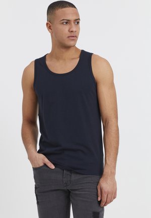 Camiseta sin mangas de color azul marino hecha de algodón, con escote redondo. Combinada con jeans ajustados de color gris oscuro con desgaste.