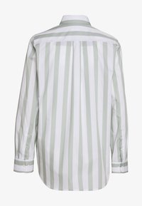 Långärmad skjorta med växelvis ljusgröna och vita vertikala ränder, krage, knäppta manschetter och en rundad nederkant.