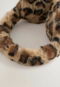 Klobúk z faux kože s leopardím vzorom, oválny tvar, jemná textúra, s hnedými a čiernymi škvrnami na svetlo béžovom pozadí.