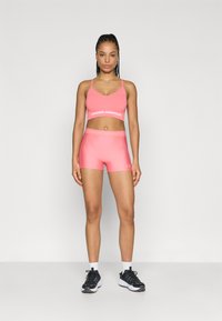 Ροζ αθλητικό σετ που περιλαμβάνει αθλητικό σουτιέν με V λαιμόκοψη και αντίστοιχα εφαρμοστά σορτς. Κατασκευασμένο από απαλό ύφασμα με αντίθετες λωρίδες λογοτύπου στις ζώνες μέσης.