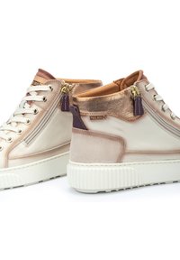 Zapatillas altas en rosa pálido y dorado metálico, con cuero suave, acentos de ante, cremalleras decorativas y una suela blanca texturizada.