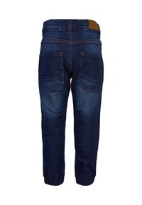 Mørkeblå denimjeans med tapered fit, med en brun lærpatch i livet og to baklommer med skrå flapper.