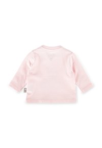 Maglietta a maniche lunghe rosa chiaro in morbido cotone. Presenta un collo rotondo e un piccolo cartellino sul lato. Texture liscia, design minimalista.