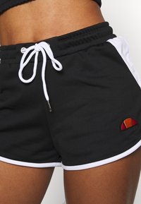 Shorts de sport noirs avec bordure blanche, taille à cordon de serrage, et logo brodé multicolore sur le côté. Tissu doux et coupe décontractée.