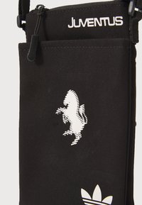 Sort stofpose med et hvidt Juventus-logo øverst og et stiliseret hvidt hestemotiv på fronten, med lynlåslukning.