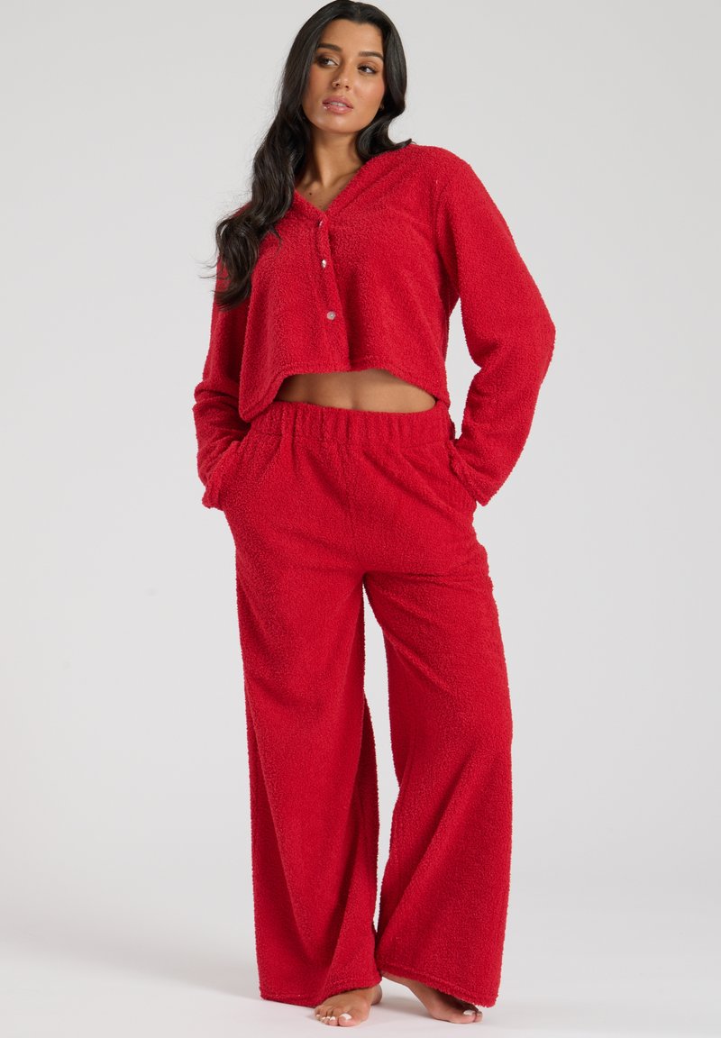 Rød fleece loungewear-sæt bestående af en cropped, knap-op top med hætte og løstsiddende, elastisk-liv bukser for komfort.