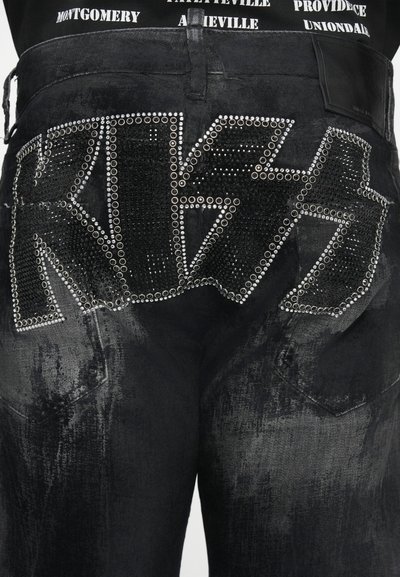 Vaqueros de mezclilla negra con adornos de piedras brillantes que forman la palabra "KISS" en la parte trasera. Acabado texturizado con desgaste visible.