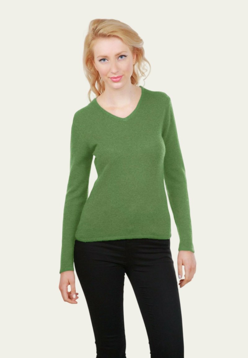 Pull vert en V fabriqué à partir d'un tissu doux et texturé, avec des manches longues et une silhouette ajustée, associé à un pantalon noir.