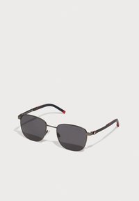 Occhiali da sole quadrati in metallo con lenti scure. Presentano una montatura nera, aste testurizzate e dettagli rossi. Design leggero per il massimo comfort.