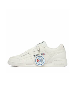 Biały niski tenis Reebok z sznurowadłami, logo po boku i na pięcie oraz okrągłą zawieszką zwisającą ze sznurowadła z niebieskim i czerwonym wzorem.