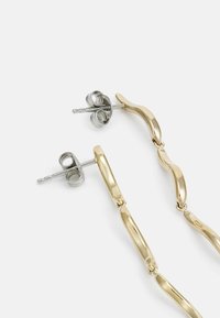 Guldtonade örhängen med varierade former, inklusive släta vridningar och avlånga länkar, med silverfärgade postbak för säker bärning.