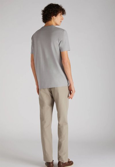 Maglietta grigia a girocollo con maniche corte, abbinata a pantaloni beige; tessuto liscio con vestibilità comoda e spacchi laterali.