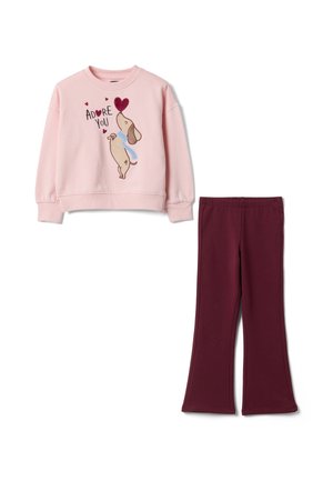 Pinkes Langarm-Sweatshirt mit Hunde- und Herzmotiv und dem Text "Adore You", kombiniert mit dunkelroten ausgestellten Hosen.