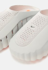 Ανοιχτό γκρι πέδιλα με σχέδιο με οπές και στρογγυλεμένες άκρες. Διαθέτουν υφή στην σόλα και διακριτικό λογότυπο. Κατασκευασμένα από μαλακό καουτσούκ.