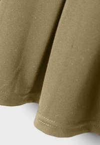 Tissu en coton kaki avec une texture lisse, présentant un ourlet arrondi et des détails de couture subtils le long des bords.