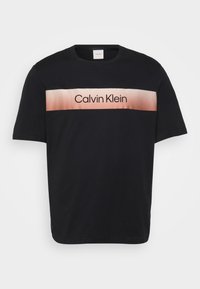 Juodas medvilnės marškinėliai su horizontaliu šviesiai rožiniu gradientu ir juodu užrašu "Calvin Klein". Trumpomis rankovėmis, apvaliu kaklu.