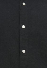 Μαύρο πουκάμισο με κουμπιά από υφή υφάσματος, με έξι λευκά κουμπιά στο μπροστινό μέρος και γιακά, με απλό και καθαρό σχέδιο.