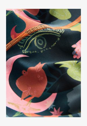 Multicolored fabric featuring abstract floral and eye patterns. Neat orange stitching along the edges adds contrast to the dark background.