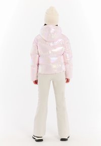 Iridescent lyserød pufferjakke med hætte, der har et quiltet design og elastisk kant. Sammen med hvide klokkeformede bukser og sorte støvler.