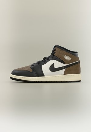 High-top Nike Air Jordan sneaker med sorte, hvide og brune ruskindspaneler, sort swoosh og hvid mellemsål på neutralt baggrund.