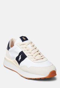 Sneakers atletici bianchi e beige con una striscia blu navy, lacci beige, suola in gomma e logo ricamato sulla linguetta.