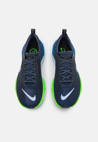 Pantofi sport Nike cu un schemă de culori albastră și verde, țesătură texturată, sistem de șireturi cu cinci găuri și logo-ul distinctiv pe lateral.