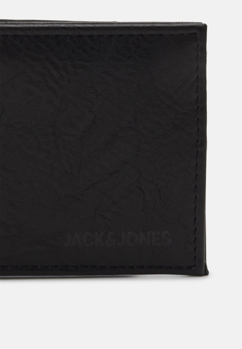 Portefeuille en cuir noir avec une surface texturée, présentant un logo embossé discret et une couture contrastante le long des bords.