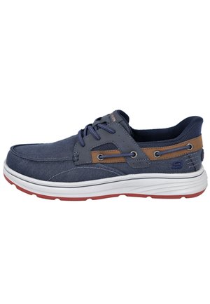Zapatilla deportiva casual azul marino con suela blanca, acento de cuero marrón, paneles de malla, cierre con cordones y suela exterior con dibujo rojo.
