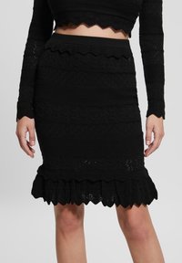 Jupe crayon noire en tricot avec des motifs texturés, ourlet festonné et design côtelé. Le tissu a une légère élasticité pour un ajustement parfait.
