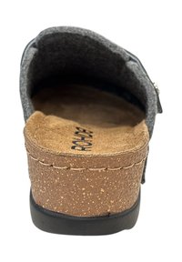 Grijze instap-schoen van vilt met een kurken middenzool en een bruine suede binnenzool. Zwarte rubberen buitenzool. Heeft een gestikte bovenkant en een verstelbare riem.