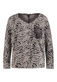 Czarny i szary top w paski zebry z długimi rękawami, dekoltem w serek i detalem z cekinowej kieszonki po lewej stronie. Miękka tkanina o luźnym kroju.