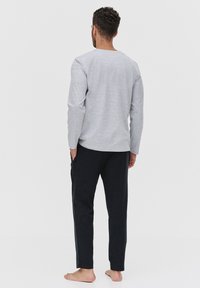 Szary longsleeve z okrągłym dekoltem, w połączeniu z czarnymi spodniami. Oba elementy są wykonane z miękkiego materiału, o swobodnym kroju.