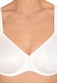 Reggiseno bianco liscio a copertura completa con ferretto, indossato da una persona, dotato di spalline regolabili e di un piccolo fiocco decorativo al centro.