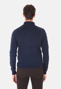 Maglione lavorato a maglia blu navy con colletto, caratterizzato da un design aderente e polsini a coste, visto dal retro. Texture morbida, dettagli minimi.