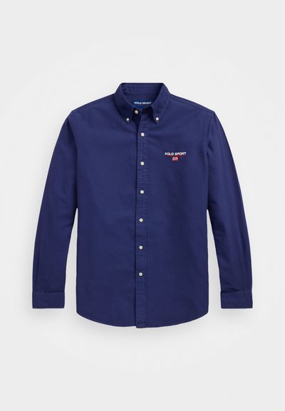Kreklu pogas, tumši zils, izgatavots no kokvilnas. Tam ir klasiskā apkakle, garas piedurknes un neliels izšūts "Polo Sport" logotips uz krūšu.