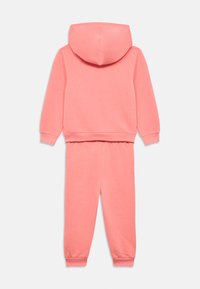 Ροζ βαμβακερή φόρμα που περιλαμβάνει φούτερ με κουκούλα και ταιριαστό παντελόνι με ελαστικές μανσέτες, λεία υφή και casual σχεδιασμό.